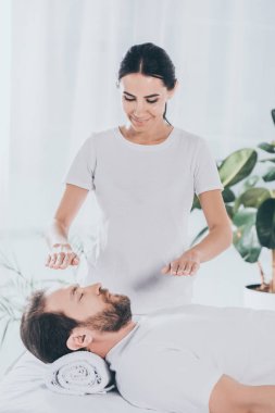 kapalı gözlerle sakallı adam sakinleştirmeye reiki oturum yapıyor gülümseyen genç şifacı 