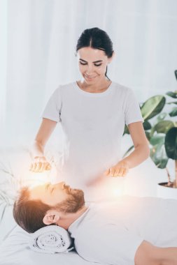 kapalı gözlerle sakallı adam sakinleştirmeye reiki oturum yapıyor gülümseyen genç kadın şifacı 