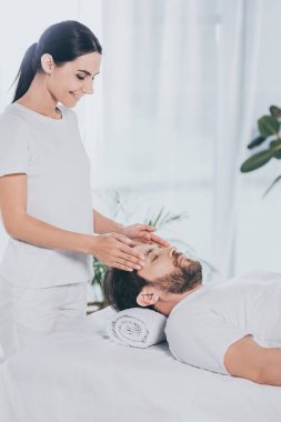 kapalı gözlerle sakallı adam sakinleştirmeye reiki tedavi oturum gülümseyen genç kadının yapması