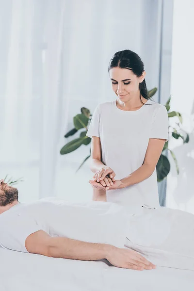 Sorridente Jovem Reiki Curandeiro Segurando Mão Homem Barbudo Calma — Fotografia de Stock