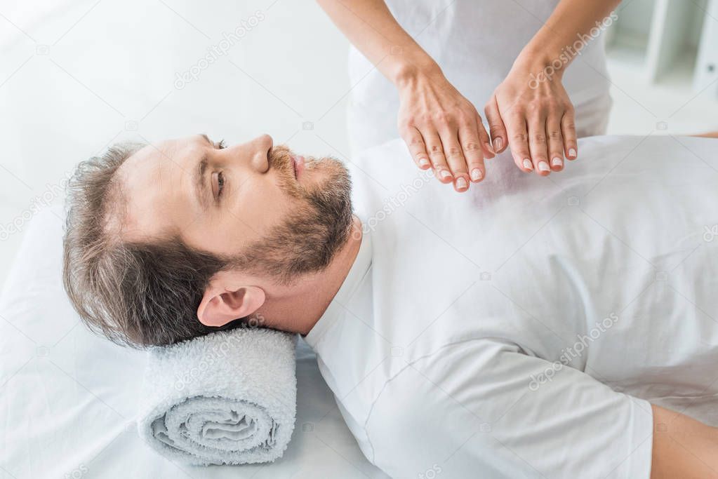 high angle view of bearded man receiving reiki treatment