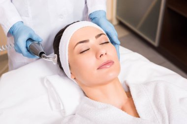 Güzellik salonunda darsonvalization cihazların yakınında kadın yüz tutan beatician