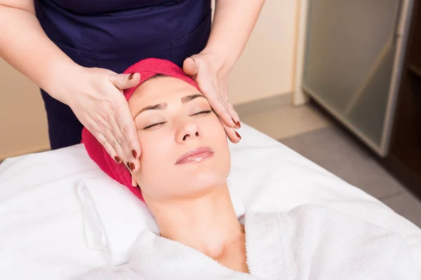 Esteticista Haciendo Masaje Facial Manual Mujer Con Toalla Roja Cabeza — Foto de Stock