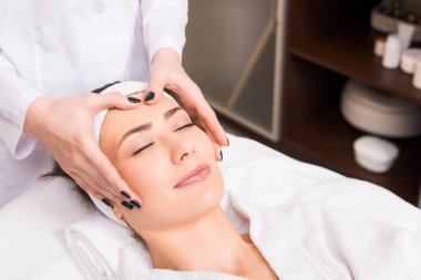 beautician doing manual massage on woman face at beauty salon