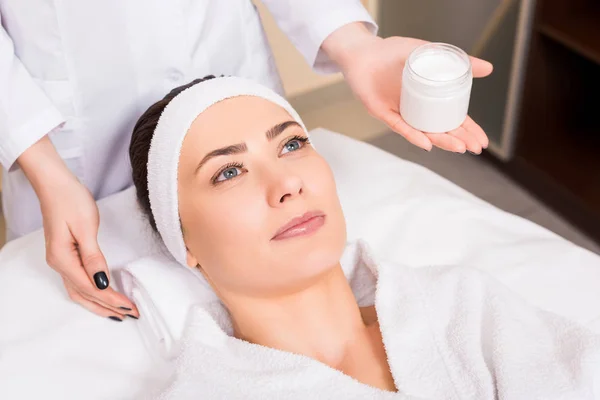 Esteticista Segurando Garrafa Creme Cosmético Perto Mulher Deitada Roupão Banho — Fotografia de Stock