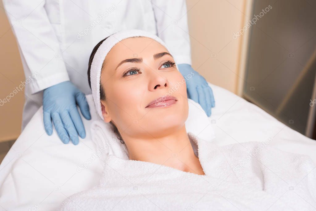 beautician standing behind woman laying at beauty salon