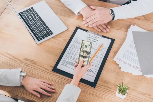 cropped view of businesswoman giving  money to worker, compensation concept