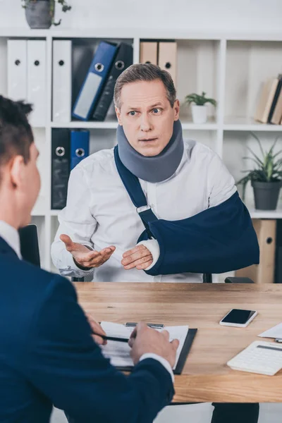 Middle Aged Worker Neck Brace Broken Arm Sitting Table Talking — Stock Photo, Image