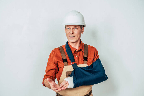 repairman with arm bandage standing on white background