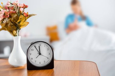 saat, çiçek vazo ve hastane odasında yeni doğan bebek ile anne