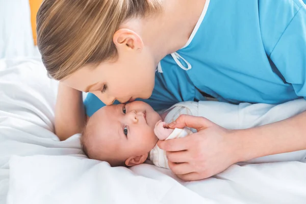 Young Mother Kissing Adorable Newborn Baby Lying Bed — Stock Photo, Image