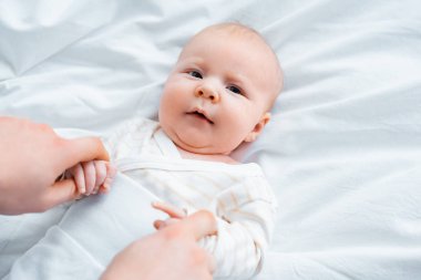 Anne tutuşup sevimli bebek bebek beyaz yatak üzerinde yalan kırpılmış atış