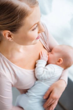 Genç anne emzirme bebek bebek evde gülümseyen, yüksek açılı görünüş