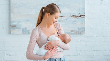 beautiful smiling young mother breastfeeding baby at home   clipart