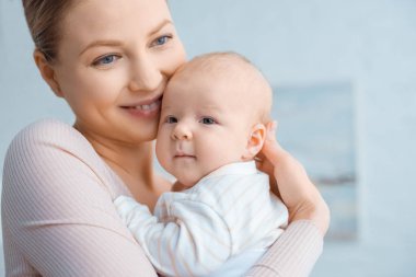 mutlu genç anne bebek sarılma ve uzağa arıyorsunuz