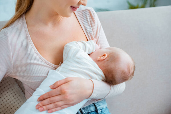 cropped shot of young woman breastfeeding infant daughter at home