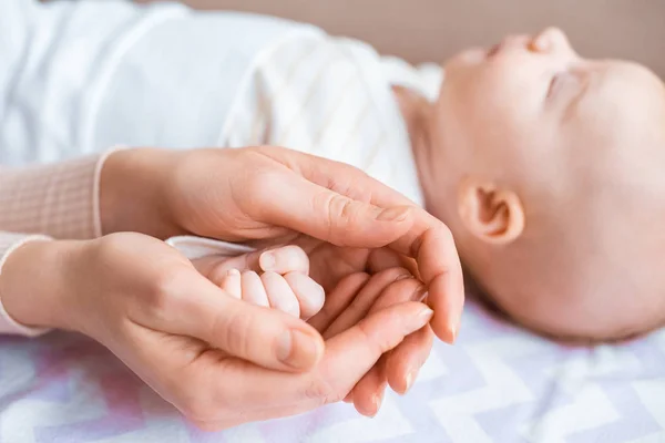 Recortado Disparo Madre Sosteniendo Mano Adorable Bebé Acostado Sofá — Foto de Stock