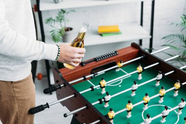 bir şişe bira futbol tablosu yakın dururken tutan adam kırpılmış görünümü