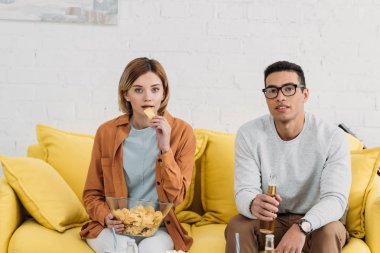 ırklararası çift zevk aperatifler ve içecekler sarı koltukta otururken 