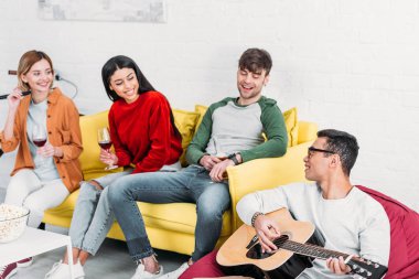 Genç karışık yarış adam için çok ırklı arkadaş akustik gitar çalmak