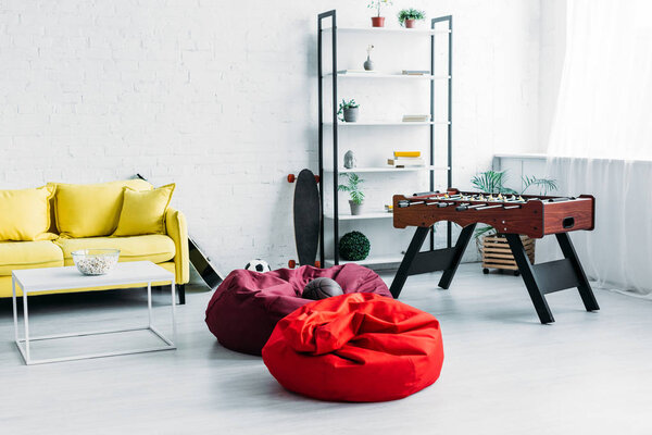 меблированная просторная гостиная со стульями, диваном и футбольным столом

