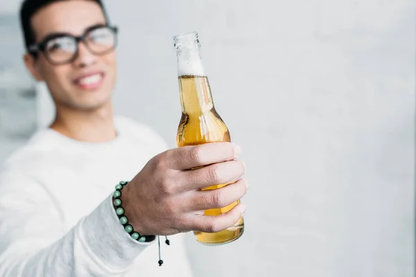 Sorrindo Homem Raça Mista Óculos Segurando Garrafa Cerveja Mão Esticada — Fotografia de Stock