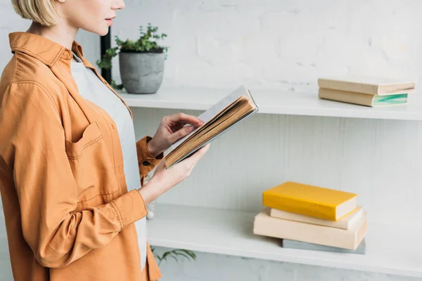 Partial View Girl Reading Book While Standing Shelving Rack — Stock Photo, Image