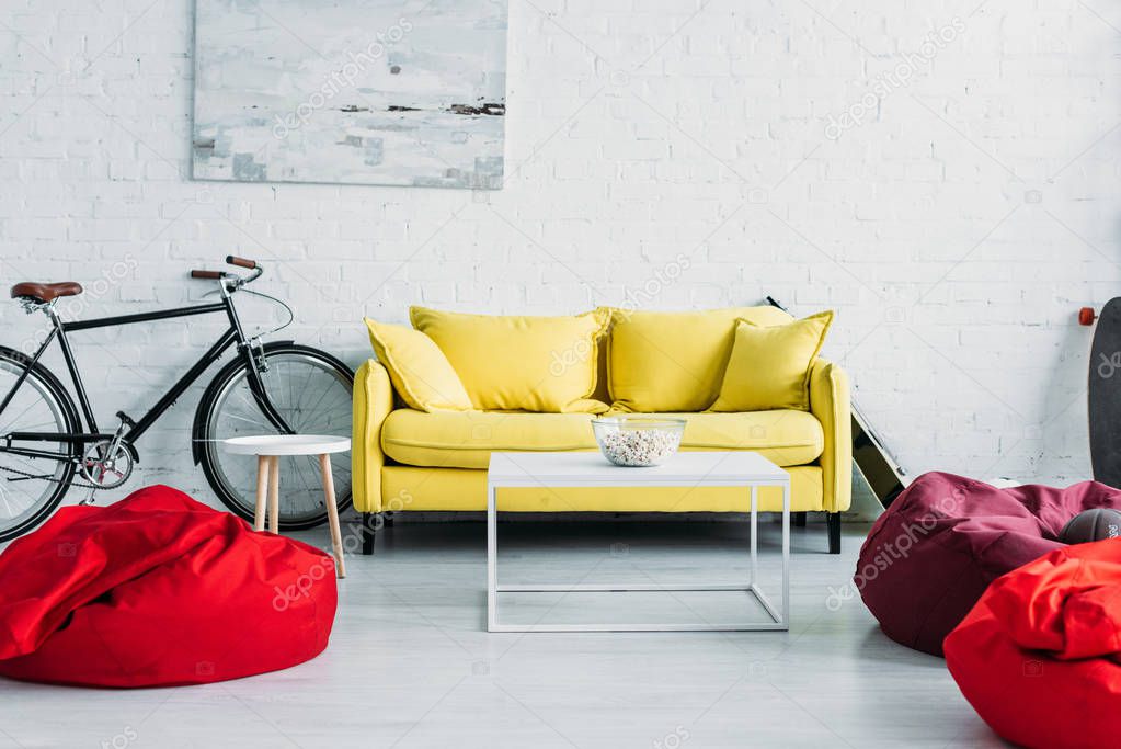 spacious furnished living room with cozy beanbag chairs and comfortable yellow sofa