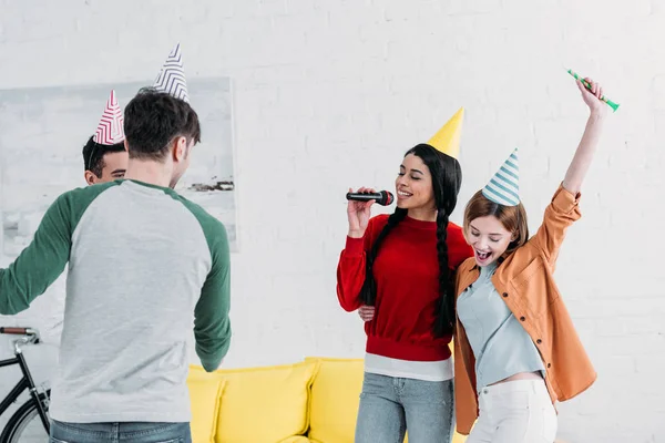 Alegres Amigos Multiculturales Coloridos Sombreros Papel Cantando Karaoke Casa Fiesta — Foto de Stock