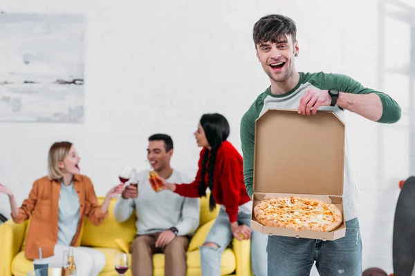 Guapo Hombre Mostrando Desempaquetado Pizza Mientras Multicultural Amigos Disfrutando Bebidas — Foto de Stock