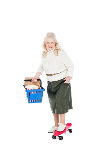 Happy Senior Woman Holding Shopping Basket Riding Penny Board Isolated — Stock Photo, Image