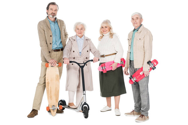 cheerful pensioners standing with skateboards near women on scooter isolated on white