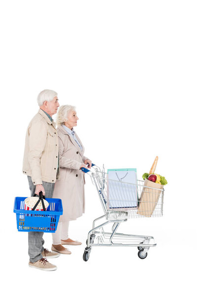 retired husband and wife walking with shopping trolley and basket isolated on white