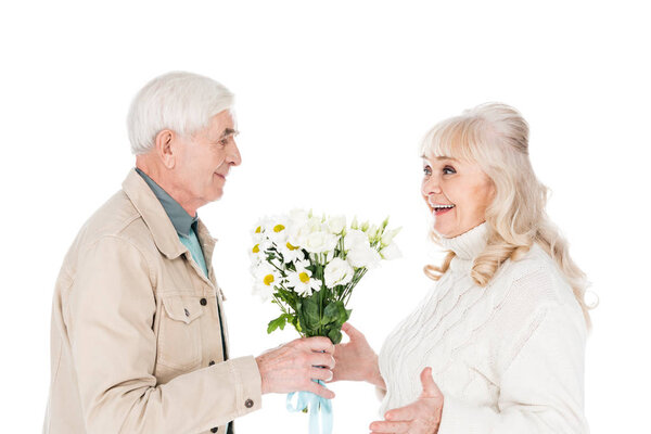 cheerful senior man giving bouquet of flowers to happy wife isolated on white