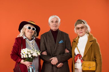Trendy üst düzey kadın arkadaş arasında emekli adam üzerinde turuncu izole ile ayakta çiçekli 