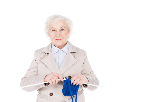happy retired  woman standing and knitting isolated on white