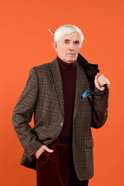 オレンジに分離されて立ったまま傘を保持しているトレンディな年配の男性 — ストック写真