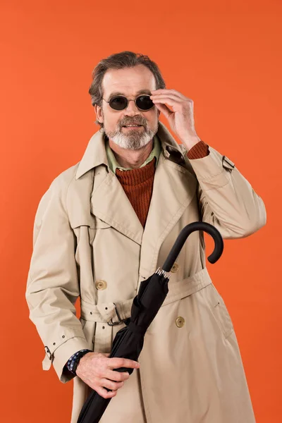 Stylish Senior Man Touching Sunglasses Holding Umbrella Isolated Orange — Stock Photo, Image