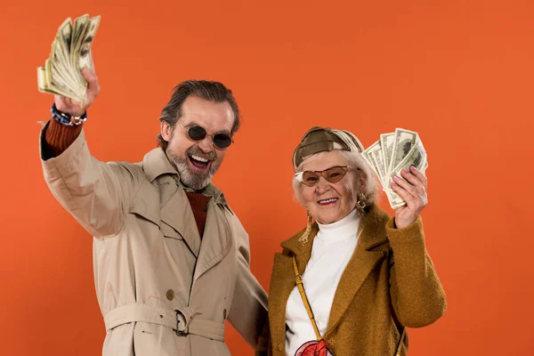 Happy Retired Couple Holding Dollar Banknotes Smiling Isolated Orange — Stock Photo, Image