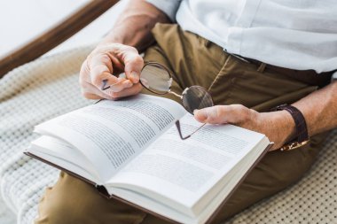 kitap okuma ve gözlük evde tutan kıdemli insanın kırpılmış görünümü