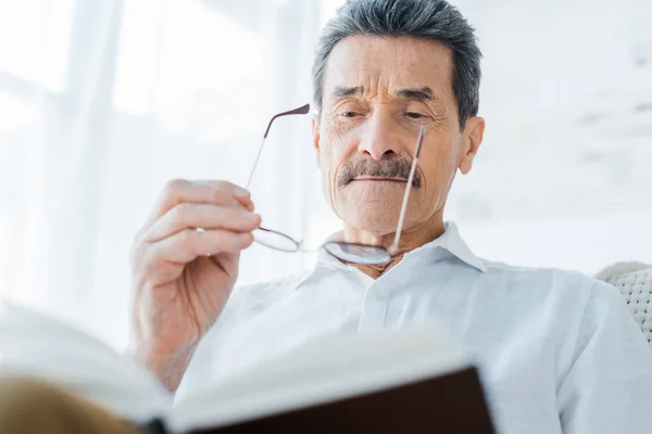 Senior Man Boek Lezen Een Bril Thuis — Stockfoto