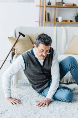 baston evde halı üzerinde oturan emekli adam