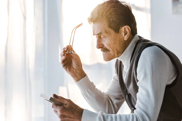 Sad Pensioner Holding Glasses Looking Photo Photo Frame While Sitting — Stock Photo, Image