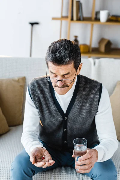 Rentner Schaut Sich Tabletten Während Hause Ein Glas Wasser Hält — Stockfoto