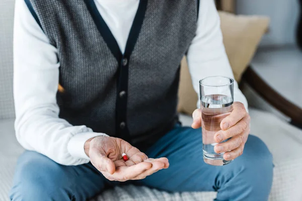 Vista Recortada Del Hombre Retirado Sosteniendo Píldora Vaso Agua Casa —  Fotos de Stock