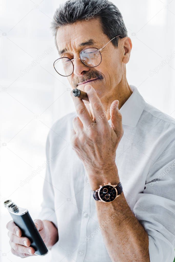 retired man with mustache smoking sigar and holding alcohol flask 
