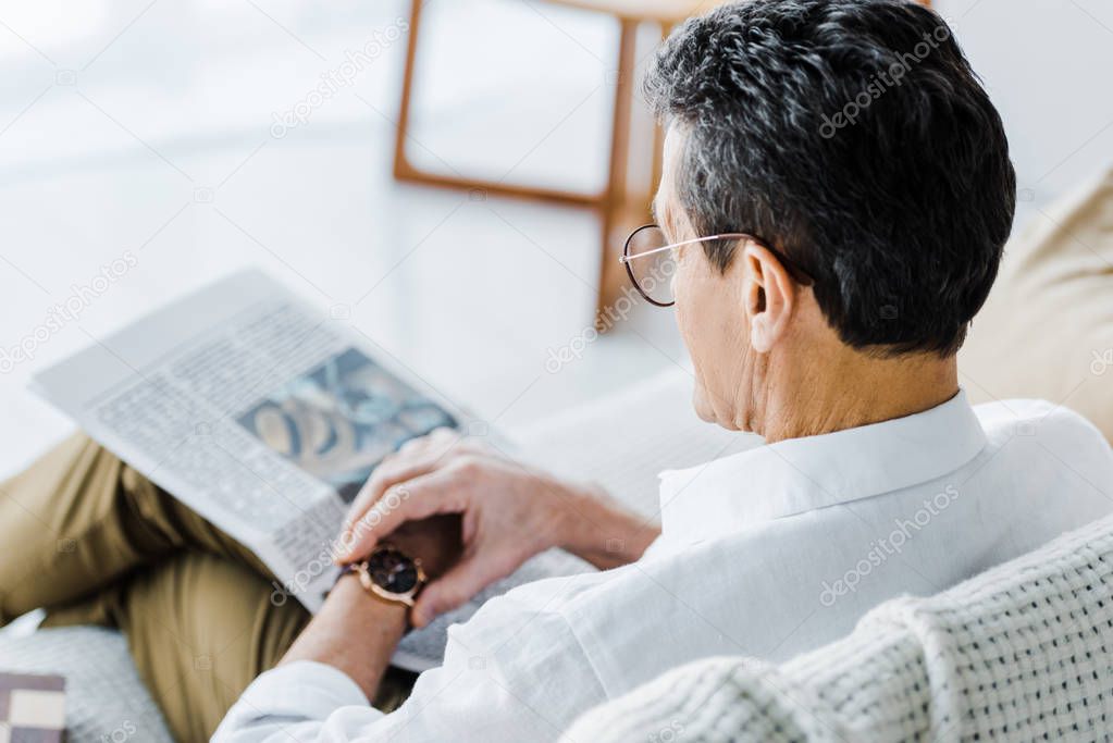 selective focus of senior man looking at watch at home