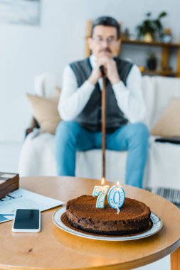 Doğum günü pastası mumlar yanan üzgün üst düzey adam arka plan üzerinde yürüyüş baston holding ile ile seçici odak