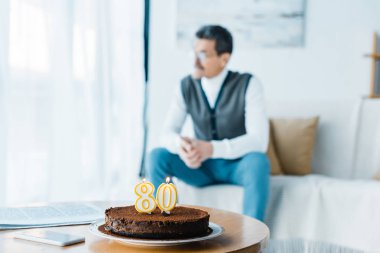 Doğum günü pastası mumlar yanan arka plan üzerinde oturan yalnız üst düzey adam ile ile seçici odak