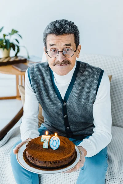 Felice Uomo Anziano Possesso Torta Compleanno Mentre Seduto Sul Divano — Foto Stock